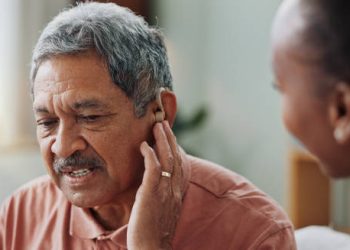 Elderly man struggling with hearing loss while touching his ear