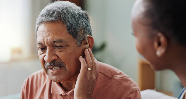 Elderly man struggling with hearing loss while touching his ear