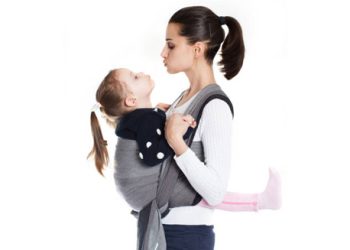 Mother carrying child in hip-healthy baby carrier during recovery from hip dysplasia