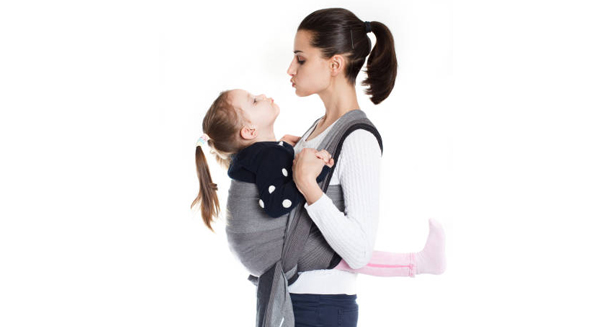 Mother carrying child in hip-healthy baby carrier during recovery from hip dysplasia