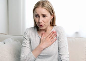 Woman experiencing shortness of breath while seated on a couch