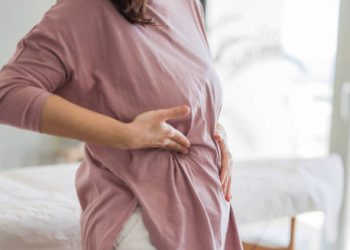 Woman holding her side in pain, indicating discomfort from a cracked rib injury.
