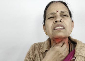 Elderly woman experiencing severe throat pain due to diphtheria