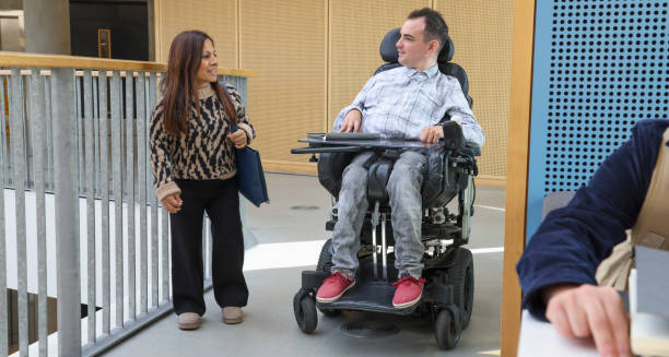 Woman with dwarfism and man in wheelchair talking in a modern building