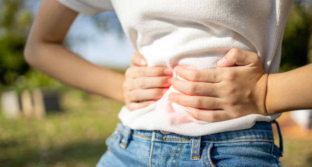 Person clutching stomach in pain outdoors