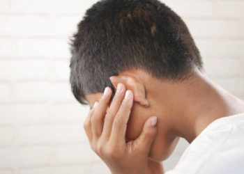 Child holding ear in pain due to complications from a burst eardrum