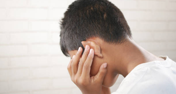 Child holding ear in pain due to complications from a burst eardrum