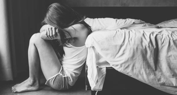 Woman sitting on the floor experiencing emotional distress due to early menopause