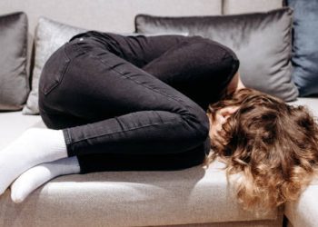 Adolescent curled up on couch showing emotional distress related to early puberty complications