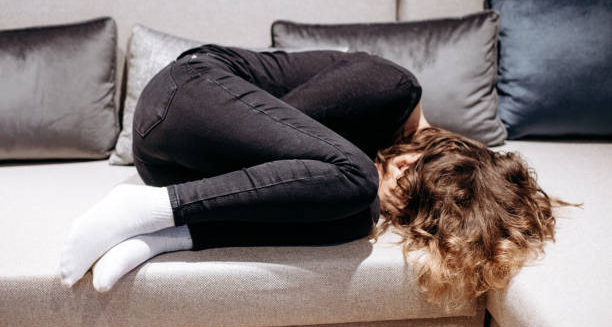 Adolescent curled up on couch showing emotional distress related to early puberty complications