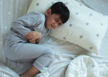 Young boy in pain holding his stomach during a febrile seizure episode