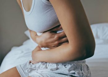 Woman clutching her abdomen, showing signs of stomach pain or cramping.