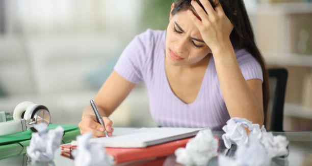 Woman stressed while writing at desk