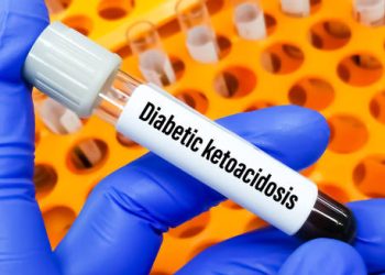 Blood sample labelled diabetic ketoacidosis held by gloved hand