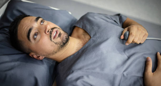 Anxious man inside MRI scanner holding emergency button, showing signs of claustrophobia.