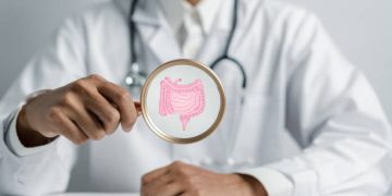 Doctor holding magnifying glass highlighting a graphic of the intestines, illustrating constipation diagnosis.