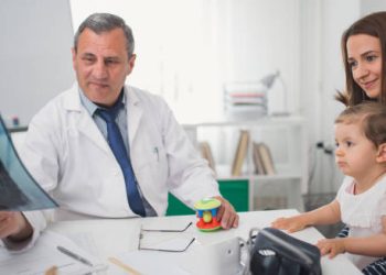 Paediatric doctor showing an X-ray to a mother and child during a consultation, representing craniosynostosis diagnosis.