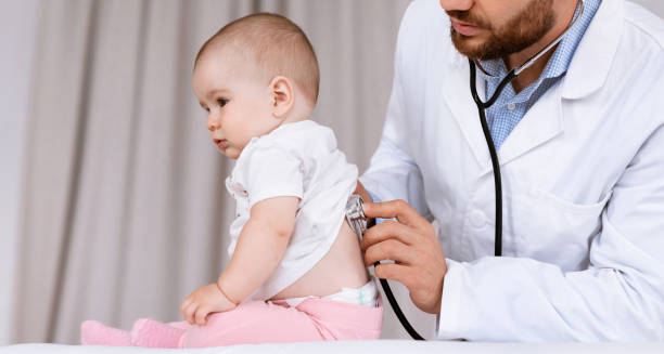 Paediatrician using a stethoscope to examine a baby’s back, assessing breathing to help diagnose croup.