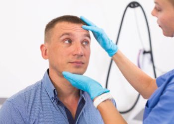 Healthcare professional examining a man's forehead and eyes for dehydration signs