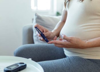 Pregnant woman checking blood sugar with a glucose meter, representing the diagnosis of diabetes in pregnancy