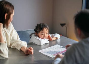 Child with short stature sitting at a table with parents and a doctor