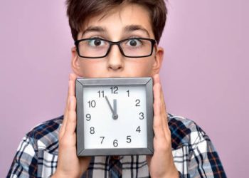 Concerned boy holding a clock symbolising early puberty diagnosis