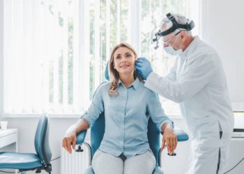 ENT specialist examining a woman's ear in a medical clinic