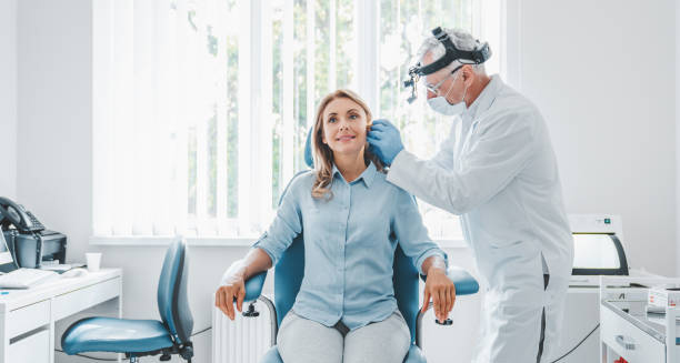 ENT specialist examining a woman's ear in a medical clinic