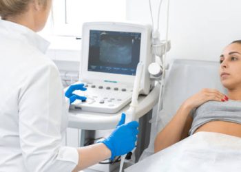 Doctor performing ultrasound scan on a concerned woman to diagnose ectopic pregnancy.
