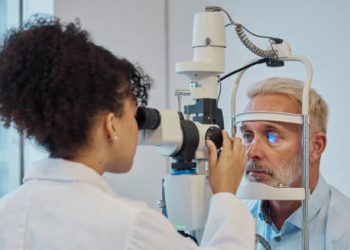 Ophthalmologist examining an older man's eye for signs of ectropion using a slit lamp.