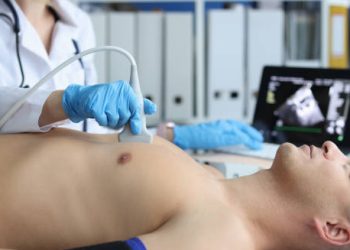 Doctor performing heart ultrasound to diagnose endocarditis in a male patient.