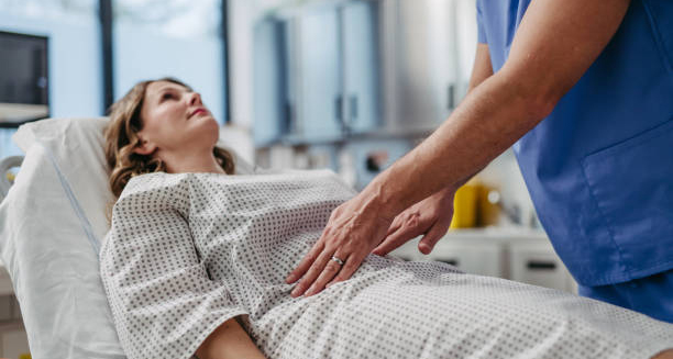 Doctor examining a woman’s abdomen during a diagnostic evaluation for endometriosis.