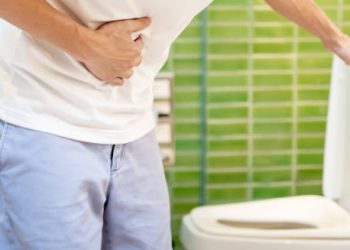 Man clutching stomach near toilet due to diarrhoea