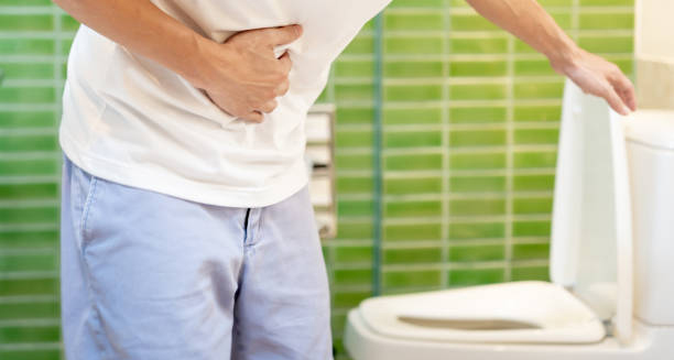 Man clutching stomach near toilet due to diarrhoea