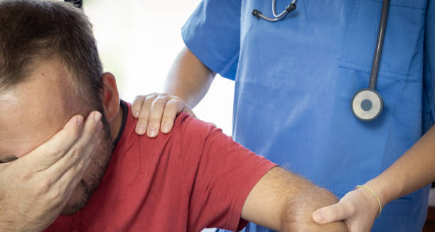 Distressed man holding his face while a healthcare professional provides support