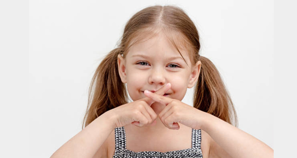 Young girl with pigtails gesturing silence with fingers