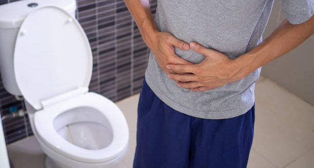 Man clutching stomach in pain next to toilet
