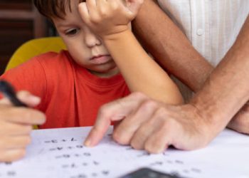 Child struggling to focus while doing homework with adult help
