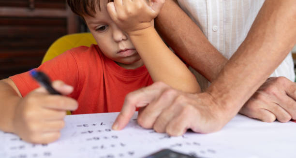 Child struggling to focus while doing homework with adult help