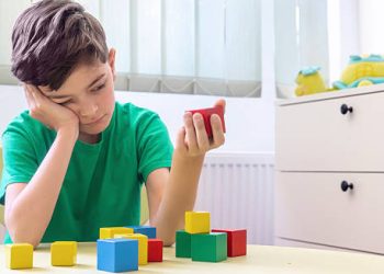 Child with dyspraxia struggling to stack colourful blocks