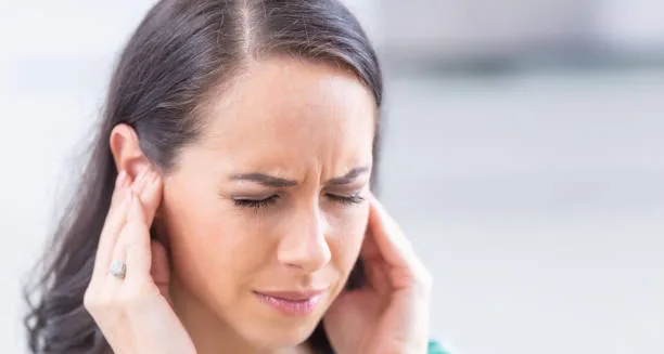 Woman in pain holding her ears due to ear infection