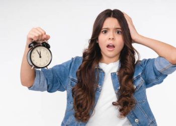 Surprised teenage girl holding a clock, symbolising early puberty
