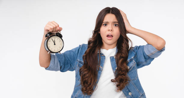 Surprised teenage girl holding a clock, symbolising early puberty