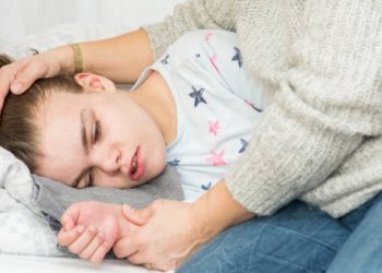 Young girl experiencing a seizure while being comforted by a caregiver