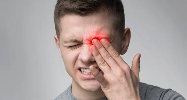 Man holding eye in pain with red inflammation indicating an eye injury