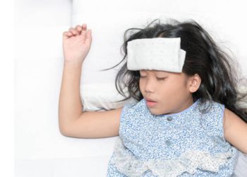 Child lying in bed with a fever compress on forehead during a febrile seizure