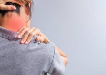 Woman holding neck and shoulder in pain with red highlighted area
