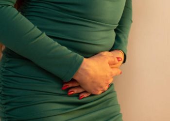 Woman in green dress clutching lower abdomen in pain