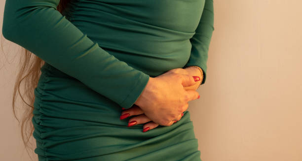Woman in green dress clutching lower abdomen in pain