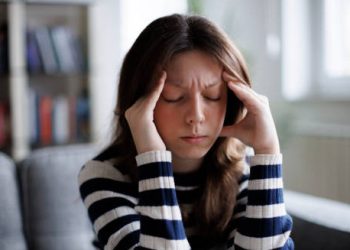 Woman holding her head in pain showing symptoms of Chiari malformation